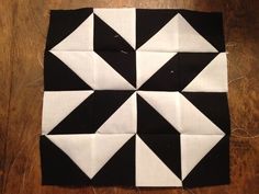 four black and white squares are arranged on a wooden surface, with one square in the middle