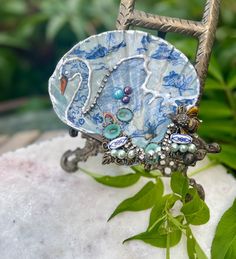 a blue and white brooch sitting on top of a rock