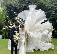 a man and woman standing next to each other in front of a large white umbrella