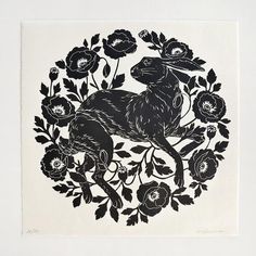 a black and white drawing of a rabbit surrounded by flowers in a circular frame on a wall