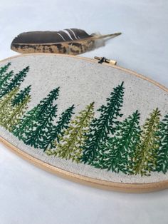 an embroidery project with pine trees and feathers