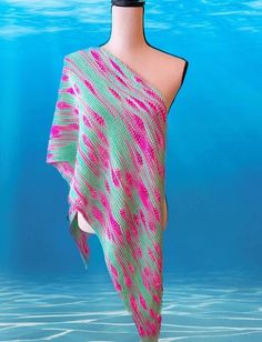 a pink and green shawl draped over a mannequin's head in the water