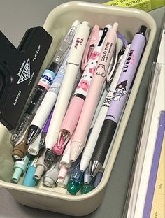 several pens and markers are in a container