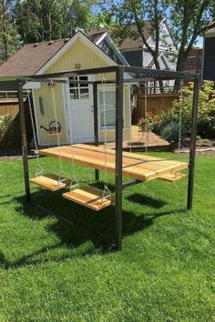 a wooden swing set in the middle of a yard