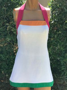 Here is a vintage 1970s white halter polyester tennis dress.Following are the measurements, Bust 32",waist 30",Hips 38",Length 29".Zips up the back.White color with pink, green , orange trim.Nice vintage condition.If you live overseas please email me before purchasing for mailing cost. Price quoted is for USA only. Please take special note of measurements. 1970s sizing was much smaller than today's standards. Tennis dresses were very short not like a regular dress. So please take special note of lengths Fitted Retro Sleeveless Halter Dress, White A-line Mod Dress, White A-line Halter Dress For Summer, White Stretch Halter Dress For Summer, Fitted Retro Summer Halter Dress, Fitted Retro Halter Dress For Summer, White Fitted Halter Dress, White Fitted Halter Neck Dress, White A-line Halter Dress For Spring