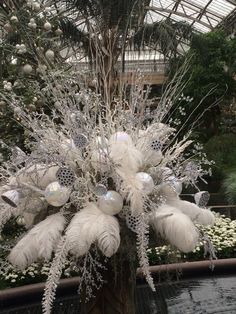 a vase filled with white flowers and feathers