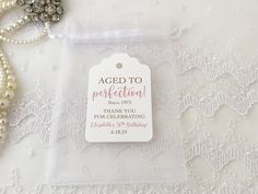 a tag that says aged to perfection with pearls and beads on the table next to it