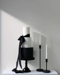 three black and white candles are on a shelf next to one another with a ribbon tied around it