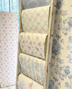 several rolls of toilet paper are stacked in an old wooden box on the floor next to wallpaper