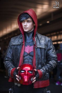 a man in a leather jacket holding a red mask