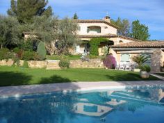 a house with a pool in front of it and trees on the lawn behind it