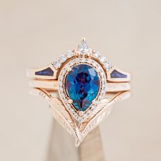 a blue diamond ring set on top of a wooden stand with diamonds around the band