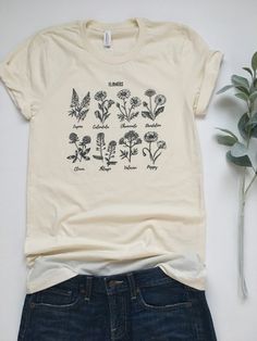 Flower Shirt. Plant Shirt. Wildflower Shirt. Plant Lady Shirt. Gardening Shirt. Garden Tshirt. Crazy Plant Lady. Adopt a Plant. Womens Tees Everyone needs a favorite tee. This tee can be just that. This one has a unique design on a natural colored tee. It's soft, comfortable, and stylish. Grab one for yourself or your wildflower-loving friend! Flower Tee Bella/Canvas or similar brand Unisex Fitted Tee, 4.2 oz 100% Combed and ringspun cotton The tee is Natural color. This tee is printed using bla Garden Tshirt, Wildflower Shirt, Crazy Plant Lady, Gardening Outfit, Nature Shirts, Gardening Shirts, Weird Shirts, Flower Shirt, Plant Lady