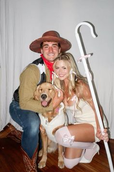 a man and woman dressed up as cowboys with a dog on their lap posing for the camera