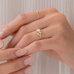 a woman's hand with two gold rings on her left and the other hand holding an engagement ring