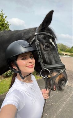 a woman is standing next to a horse wearing a helmet