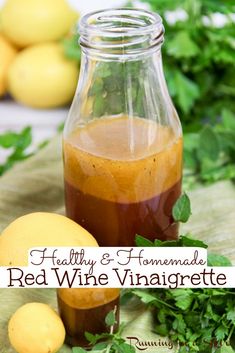 a bottle filled with red wine vinegar next to lemons and parsley on a table