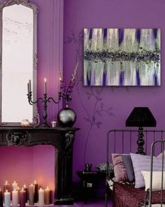 a living room with purple walls and candles on the floor in front of a mirror