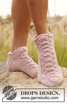 a woman's legs wearing pink knitted slippers on top of a rock