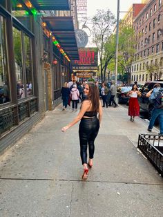 a woman walking down the street in front of a restaurant