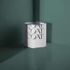 a white can sitting on top of a table next to a purple wall with the word coat over it