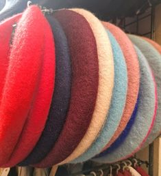 a bunch of different colored hats hanging from hooks