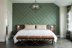 a bedroom with green walls and white bedding, wooden bench in the foreground