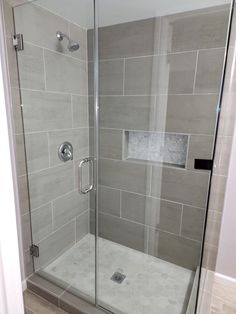 a walk in shower sitting next to a tiled wall