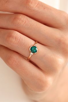 a woman's hand with an emerald and diamond ring