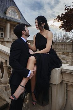 a man and woman are sitting on a balcony looking into each other's eyes