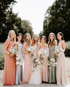 a group of women standing next to each other wearing dresses and holding bouquets in their hands