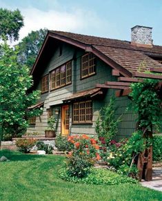 a green house with lots of flowers in the front yard