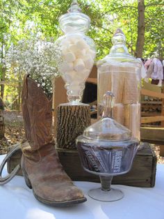 a cowboy boot sitting on top of a table next to a glass vase filled with flowers