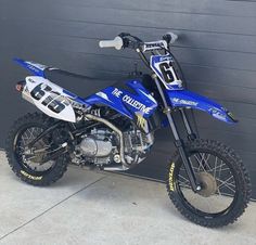 a blue and white dirt bike parked next to a garage door with the number six on it