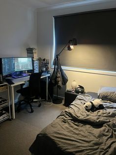 a bed room with a neatly made bed and two computer monitors on the wall next to it