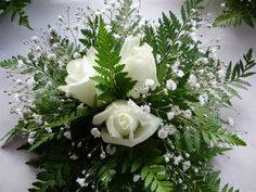 a bouquet of white roses and greenery on a table