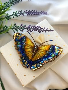 a yellow and blue butterfly sitting on top of a white napkin next to purple flowers