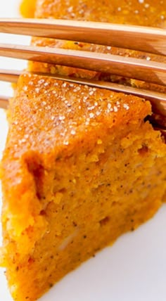 two pieces of cake on a white plate with gold forks in front of the slice