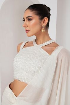 Ivory pre-draped saree crafted in metallic georgette. Paired with a sleeveless halter neck blouse with tonal crystal tassel embellishments. - Aza Fashions Blouse Designs Western, Halter Neck Designs, Blouse Halter Neck, Ivory Saree, Saree Drapes, Halter Neck Blouses, Tassel Blouse, Draped Saree, Drape Saree