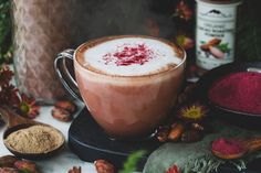 a cup filled with liquid sitting on top of a table next to nuts and spices