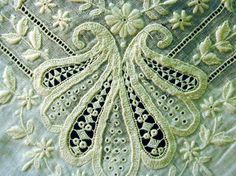 an embroidered piece of cloth with white flowers and leaves on the edge, in close up