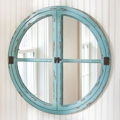 a round mirror mounted to the side of a wall next to a white and blue striped wall