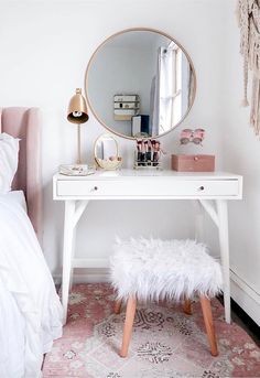 a pink and white bedroom with a vanity, bed, mirror and rug on the floor