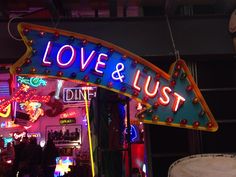 a neon sign that says love and lust hanging from the side of a store front