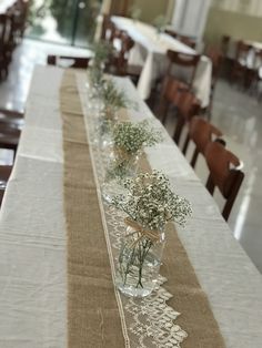 the table is set with two vases filled with baby's breath flowers and greenery