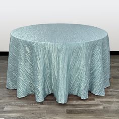 a round table with a blue cover on it sitting in front of a white wall