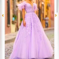 a woman in a purple dress is standing on the street and looking at the camera