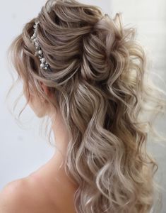 the back of a woman's head with wavy hair and pearls in her hair