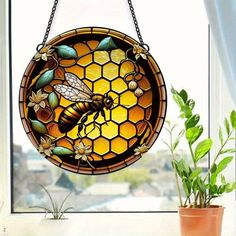 a stained glass window with a bee and honeycomb design hanging from it's side