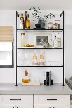 the shelves in this kitchen are filled with bottles and glasses